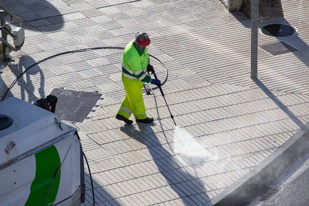 worker cleaning sidewalk with high pressure water jet machine sunny day 1920w